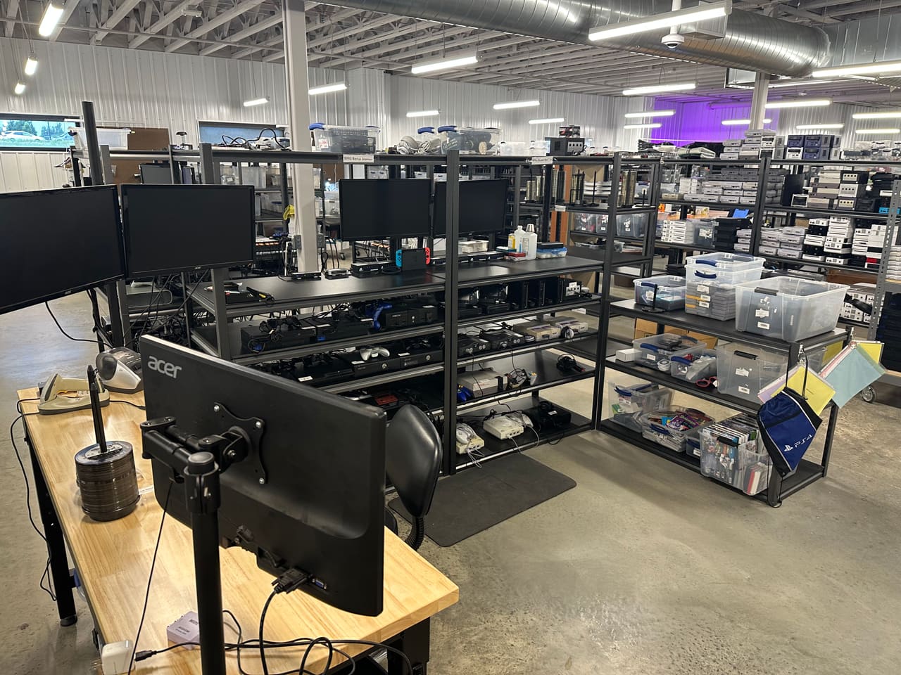 Technician testing consoles and checking condition at a workstation